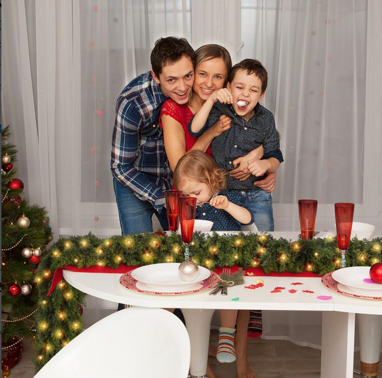 Family gathered at a holiday table decorated with the lit garland
